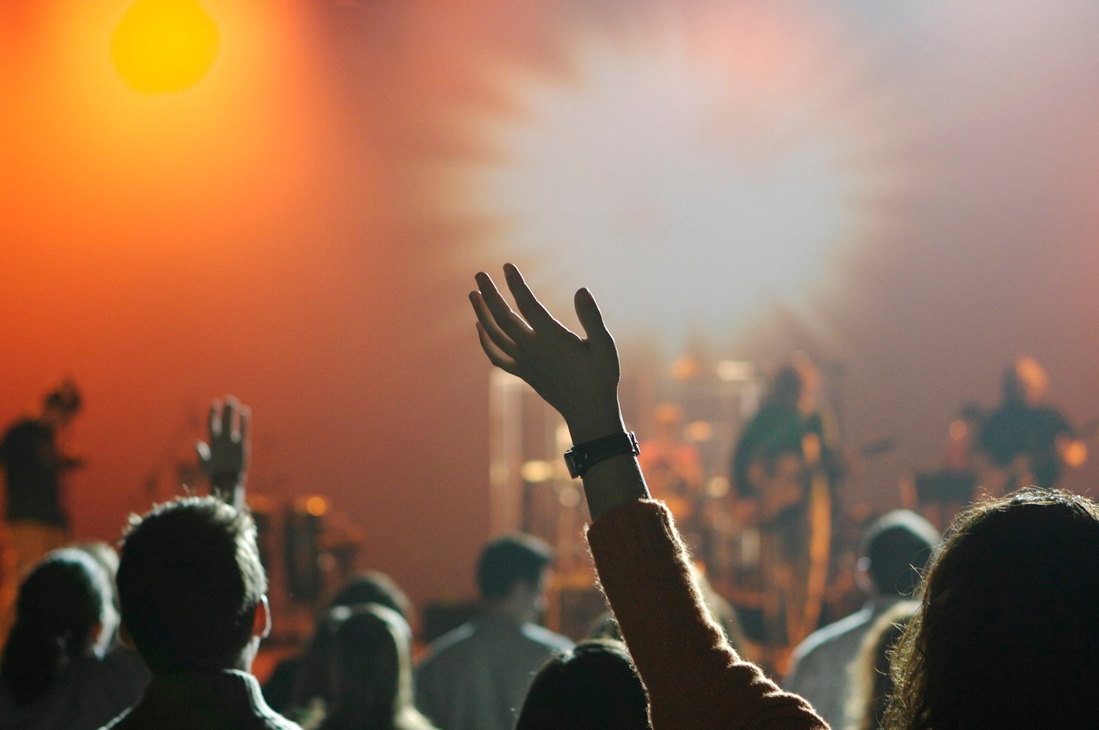 A hand raised in worship to Jesus among a gathered crowd
